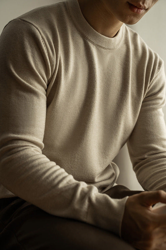 Person wearing a beige sweater with a neutral background